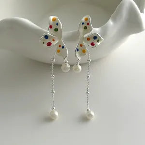 Detailed macro view of colorful polka dot flower earrings featuring long pearl tassels