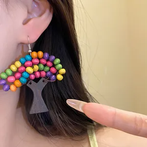 Détail d'une boucle d'oreille ethnique en forme d'arbre avec perles en bois colorées