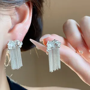 Detailed view of silver tassel earrings featuring a crumpled texture and a single pearl.