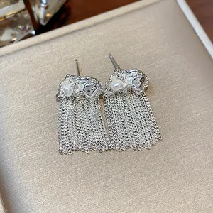 Detailed close-up showing silver wrinkled chain tassel earrings with elegant white pearls.