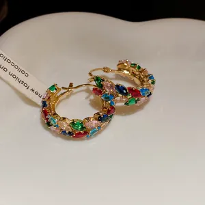 Detailed macro view of vintage multi-colored zircon wheat ear hoop earrings on a tray
