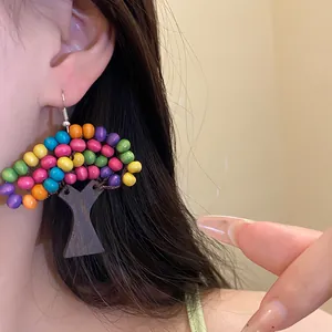 Gros plan d'une boucle d'oreille arbre en perles de bois colorées, bijou de style ethnique.