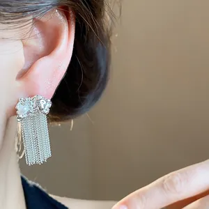 Detailed close-up of silver tassel earrings with elegant pearl accents worn on ear