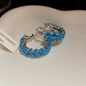 Close-up detail of vintage wheat hoop earrings featuring sparkling blue zircon stones