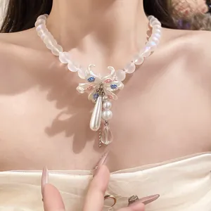 Détail d'un collier en perles dépolies avec pendentif floral porté par un mannequin