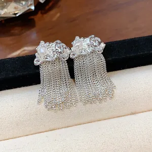 Detail of silver tassel earrings featuring pearls and unique wrinkled metal texture.