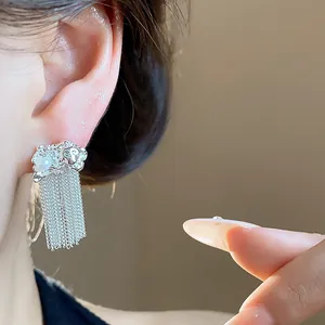 Detailed macro view of elegant silver chain fringe pearl stud earrings worn on ear.
