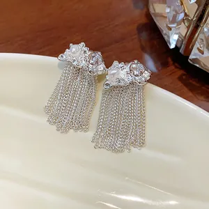 Detailed close-up of silver tassel earrings featuring white pearls and elegant crinkled texture