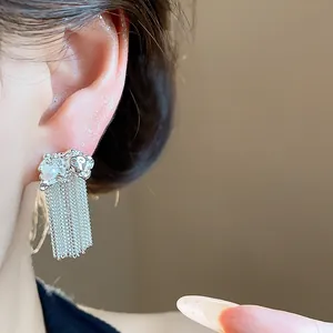 Detailed view of elegant silver tassel earrings with a pearl and wrinkled metal texture.