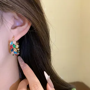 Close-up of elegant vintage court style hoop earrings featuring colorful zircons on ear