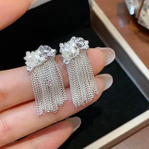 Close-up detail of silver chain tassel earrings featuring a delicate pearl and textured finish.