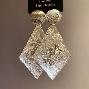 Textured silver metal diamond earrings with embossed floral pattern