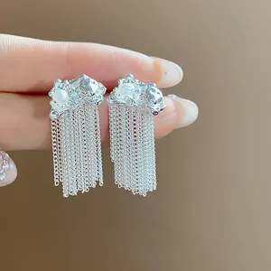 Close-up view of silver chain tassel earrings with wrinkled metal texture and pearl
