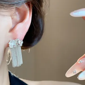 Close-up detail of silver pleated chain tassel earrings with pearl accent on model