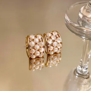 Detailed close-up of 18k gold plated stud earrings with cat's eye stones and zircons