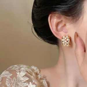Close-up detail of 18k gold plated stud earrings featuring elegant pearls and zircons