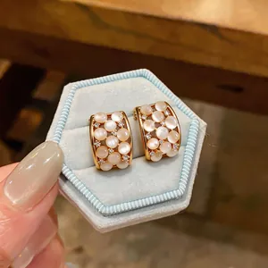 Macro view of elegant 18k gold plated hoop earrings with cat-eye stones and zircons gems.
