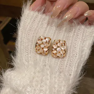 Close-up detail of luxury cat's eye stone and zircon stud earrings with 18k gold plating