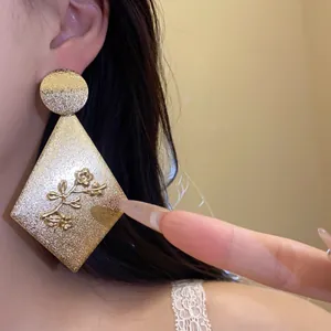 Close-up detail of the textured gold finish and floral relief on a diamond earring