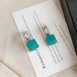 Gros plan de boucles d'oreilles carrées turquoise avec anneaux sertis de cristaux
