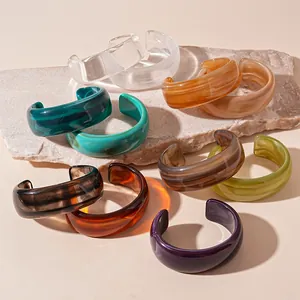 Multi-colored vintage thick resin bangles in Maillard style arranged on natural stone base.