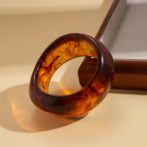Macro detail of a wide resin bracelet featuring a vintage amber tortoiseshell swirl design