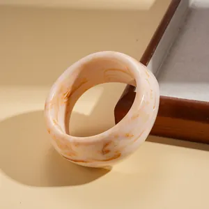 Close-up of wide irregular resin bangle with elegant cream and brown marble texture