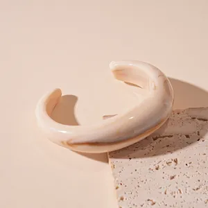 Close-up shot of a beige acrylic wave bangle featuring an elegant marbled ink-wash pattern.