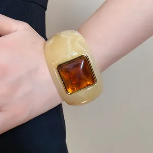 Close-up detail of a square amber stone inlay on a cream acrylic chunky bangle