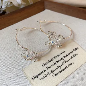 Close-up of silver-plated hoop earrings with intricate zircon butterfly charms