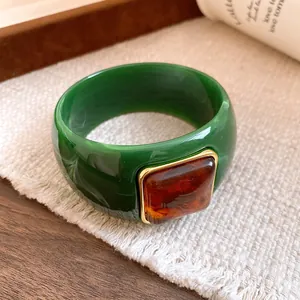 Close-up detail of a stylish green acrylic bangle with a square amber-colored resin stone