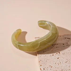 Close-up detail of an olive green irregular resin bangle with white marble texture