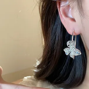 Close-up showing the intricate hollow flower design and shimmering zircon of the earring