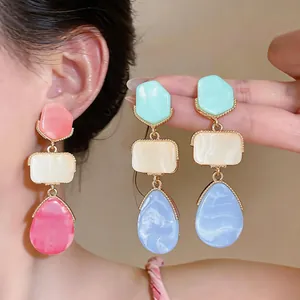 Dettaglio di orecchini pendenti in resina colorata stile dopamina con design geometrico