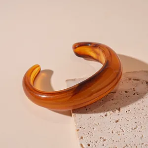 Close-up detail of a vintage irregular amber resin bangle displayed on textured stone slab