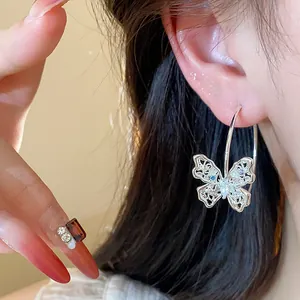 Close-up detail of a silver butterfly hoop earring with colorful zircon stones on ear