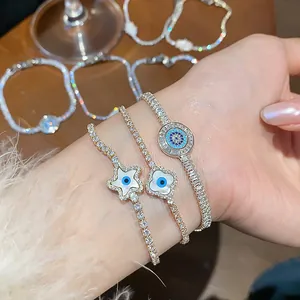 Close-up detail of three 18k gold plated tennis bracelets with sparkling evil eye charms.