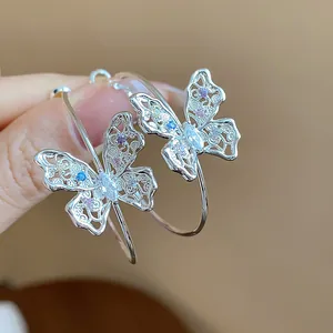 Macro detail of elegant hollow butterfly hoop earrings featuring colorful zircon stones
