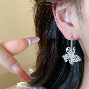Detail showing intricate hollow silver flower earring with shimmering zircon accents on model
