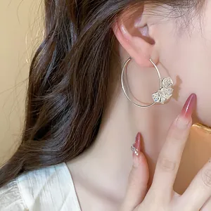 Detailed close-up of a silver hoop earring featuring an intricate openwork butterfly design.
