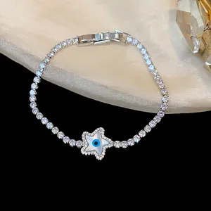Detailed view of 18k gold plated tennis bracelet with zircon star and evil eye charm.