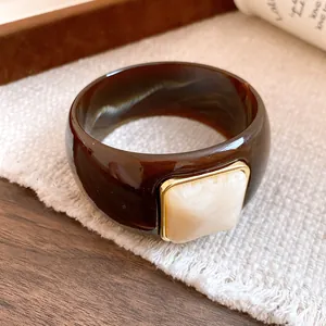 Close-up of a wide brown marbled acrylic bangle with an ivory square stone inlay detail