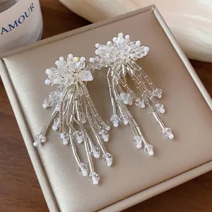Elegant glass flower tassel earrings with clear crystal beads on a beige jewelry box