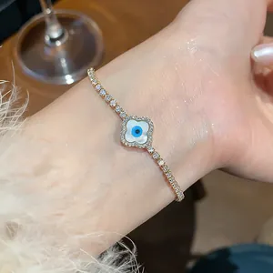 Close-up of 18K gold plated zircon bracelet with evil eye clover charm on wrist.