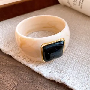 Close-up of a marbled cream acrylic bangle with a square black stone detail