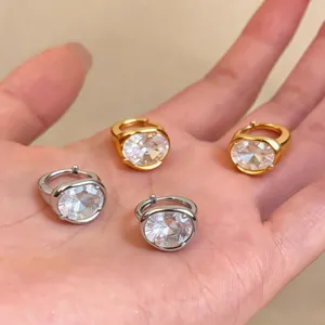 Dettaglio di orecchini a cerchio placcati in oro 18k e argento con grandi zirconi ovali.