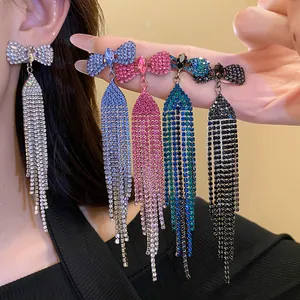 Multi-color sparkling rhinestone bow long tassel drop earrings on model ear and hand.