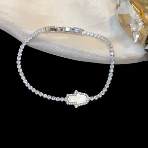 Macro detail of Hamsa hand bracelet with cubic zirconia and shell inlay on silk.