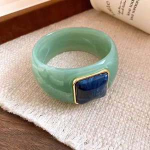 Close-up detail of green acrylic bangle featuring square blue marble inlay and gold frame