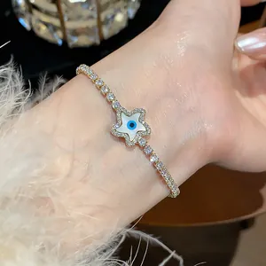 Macro view of an 18k gold plated star bracelet with zircon evil eye detail on a wrist.